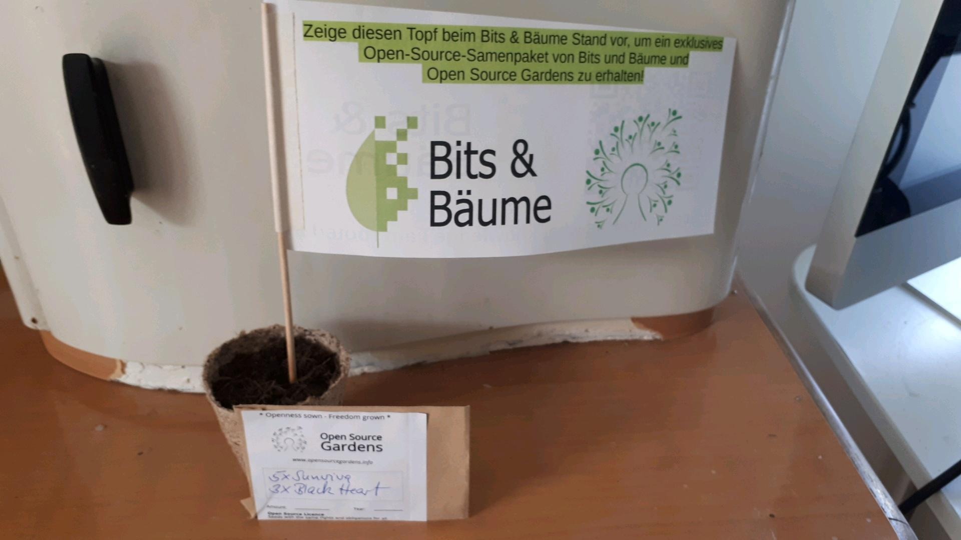 The picture shows a seedbag with open Source Seeds and a flag with an OSG logo and a logo of Bits&Trees as part of a game in which you get seeds if you find the flag. 